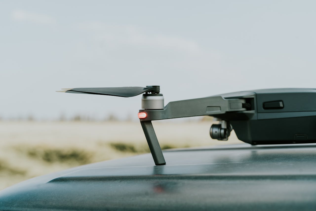 gallery-5 A detailed view of a drone resting on a car roof in a summer outdoor setting.